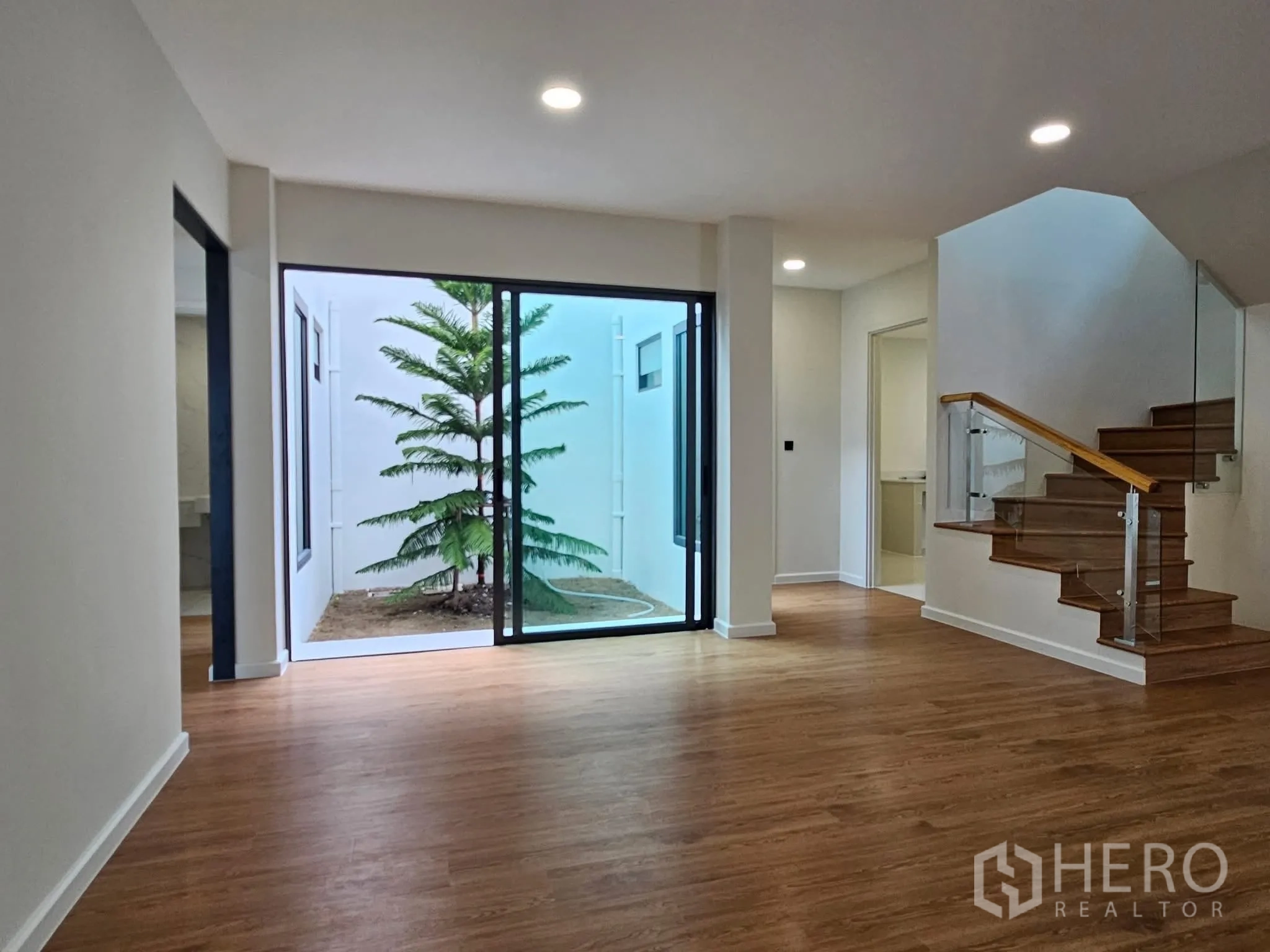 บ้านเดี่ยว for sale in Lat Phrao, Bangkok - พื้นที่นั่งเล่นเปิดสู่คอร์ทยาร์ดส่วนตัวผ่านประตูกระจกบานเลื่อน มีต้นไม้ตกแต่ง
