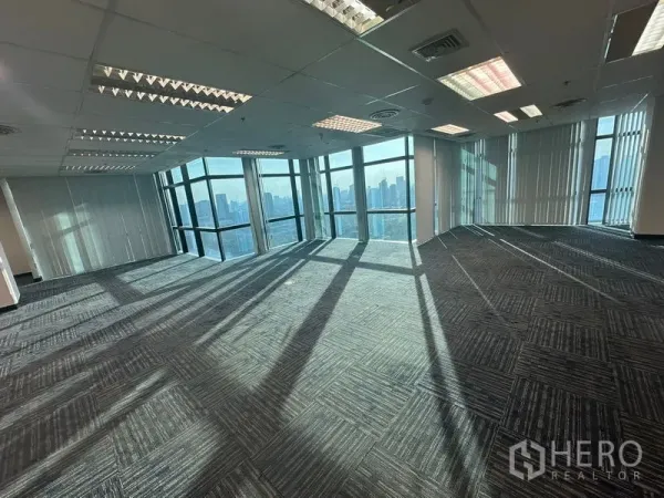 Office Space for rent in Watthana, Bangkok - Open-plan office floor with carpet tiles and wraparound glass overlooking the city.