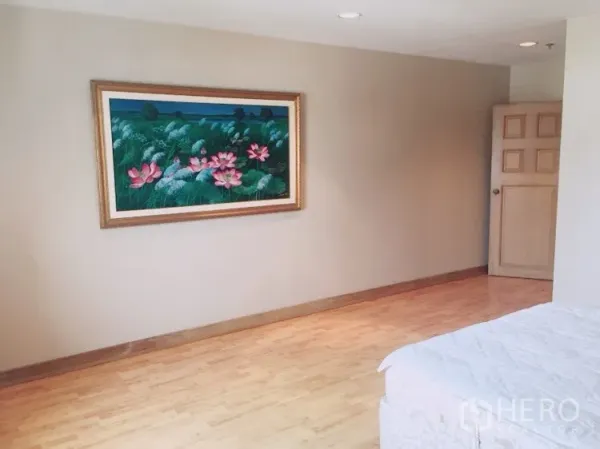 Condominium for rent in Watthana, Bangkok - Cozy bedroom wall with lotus painting and partial bed on wooden flooring.