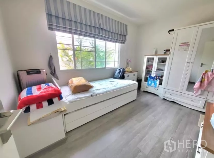 Townhouse for rent in Bang Phli, Samut Prakan - Second bedroom with large window, built-in storage and wood-look flooring.
