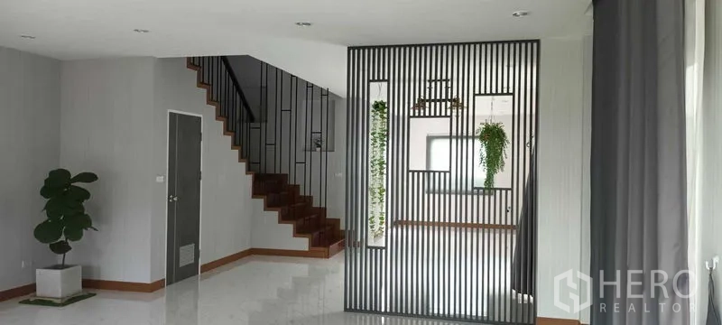 联排别墅 出租或出售在Saphan Sung, Bangkok - 采光充足的开放式客厅，金属格栅隔断与木质楼梯。