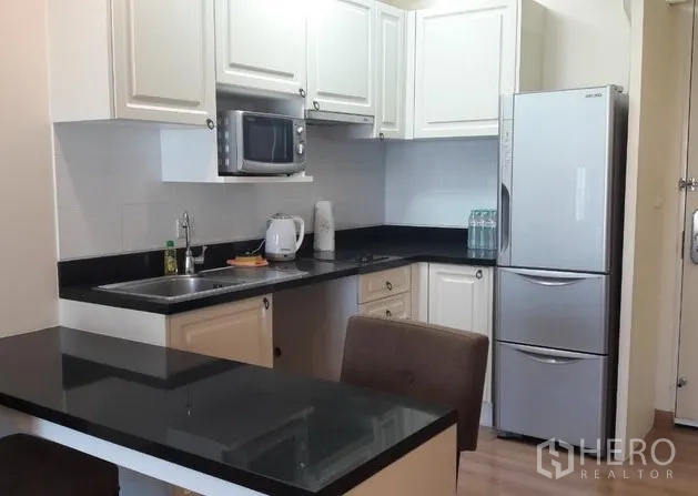 คอนโด ให้เช่าในPathum Wan, Bangkok - ครัวกะทัดรัด ตู้สีขาว ท็อปหินแกรนิตสีดำ ไมโครเวฟ ตู้เย็น และเคาน์เตอร์บาร์