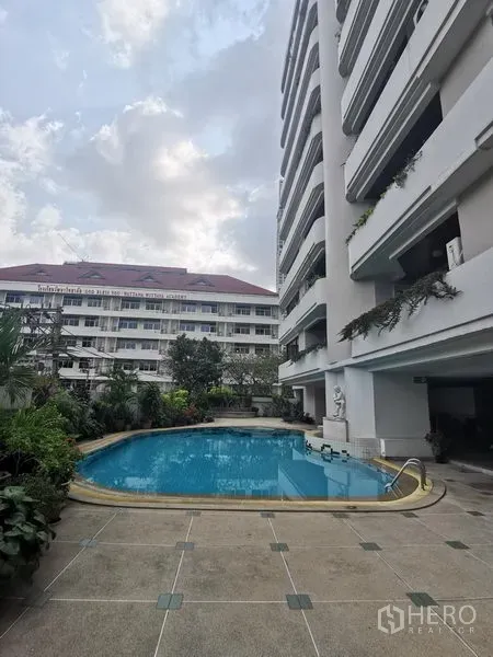 Condominium for rent in Watthana, Bangkok - Outdoor swimming pool beside a residential condominium with greenery and balconies.
