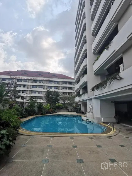 Condominium for rent in Watthana, Bangkok - Outdoor swimming pool beside a residential condominium with greenery and balconies.