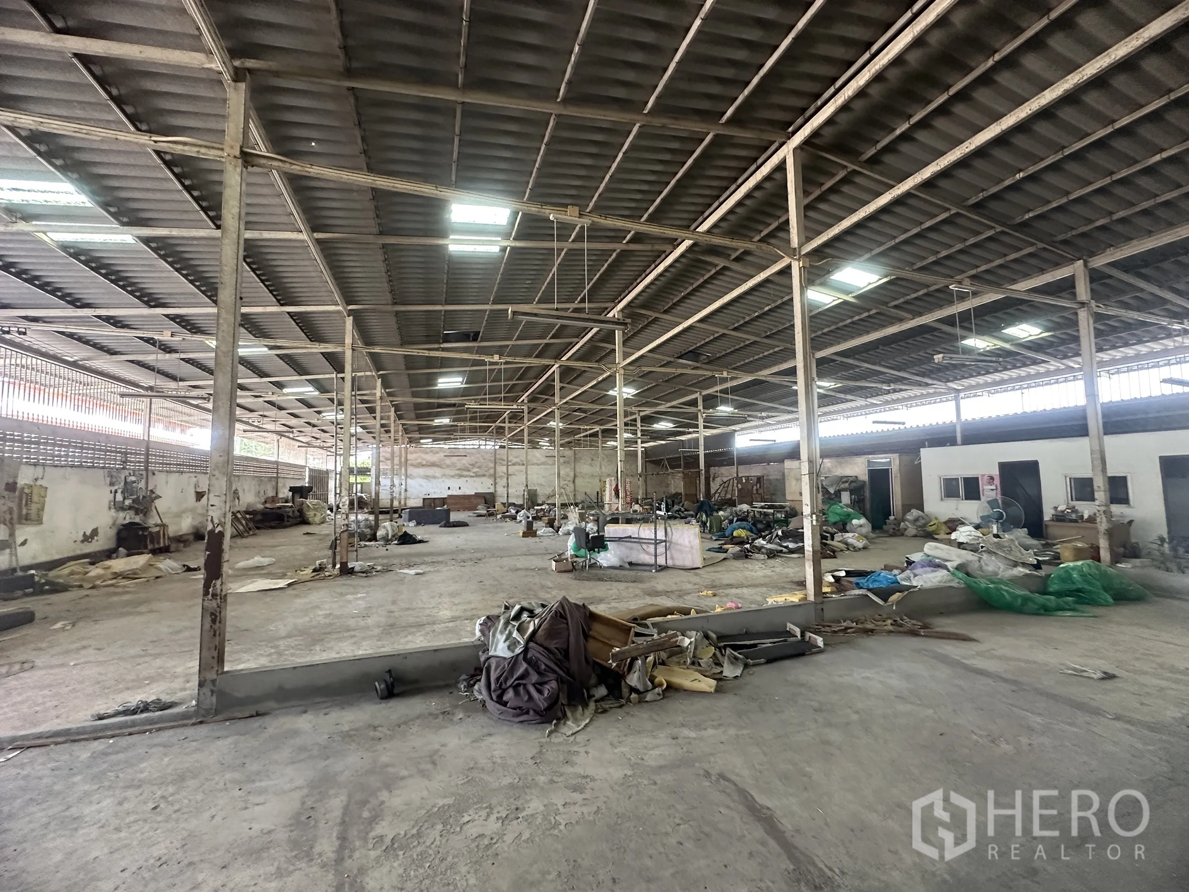 Warehouse for rent in Lam Luk Ka, Pathum Thani - Open-plan interior with concrete slab and partitioned rooms along the wall.