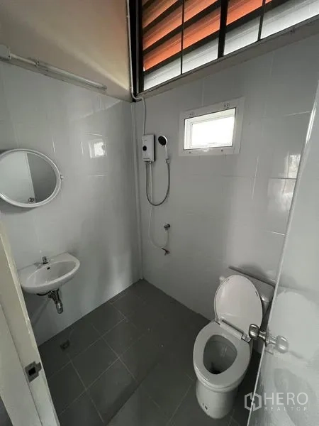 Warehouse for rent in Suan Luang, Bangkok - Clean tiled bathroom with toilet, sink and wall-mounted shower heater.