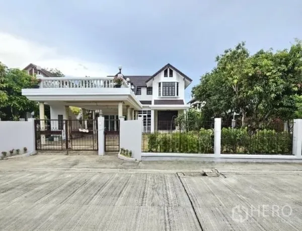 Detached House for sale in Saphan Sung, Bangkok - Front exterior view of a gated detached house with covered parking and landscaped greenery.
