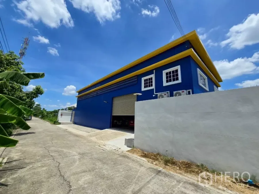 คลังสินค้า ให้เช่าหรือขายในKhlong Toei, Bangkok - คลังสินค้าสีน้ำเงินตัดเหลืองแบบเดี่ยว พร้อมกำแพงรั้วและถนนเงียบ ภายใต้ท้องฟ้าใส