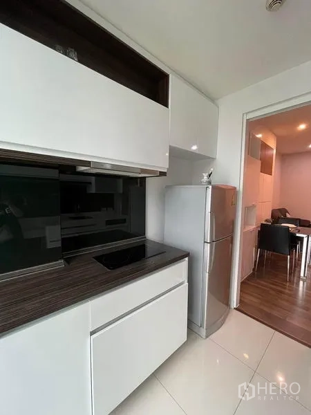 คอนโด ให้เช่าหรือขายในPhra Khanong, Bangkok - ครัวพร้อมเตาไฟฟ้า ท็อปสีเข้ม และตู้เย็นขนาดใหญ่