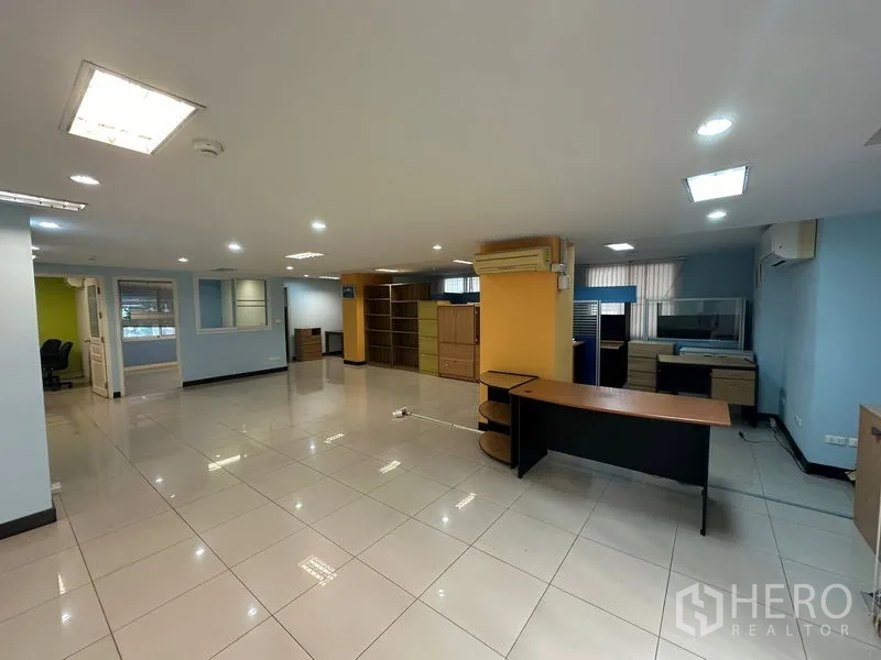 สำนักงาน ขาย - พื้นที่สำนักงานแบบเปิดมีโต๊ะ เสาเหลือง และไฟดาวน์ไลท์
