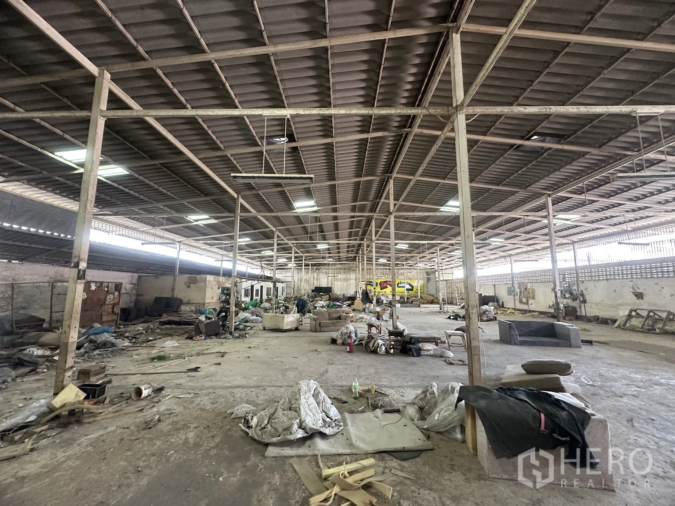 Warehouse for rent in Lam Luk Ka, Pathum Thani - Deep warehouse view with overhead strip lights and multiple support posts.