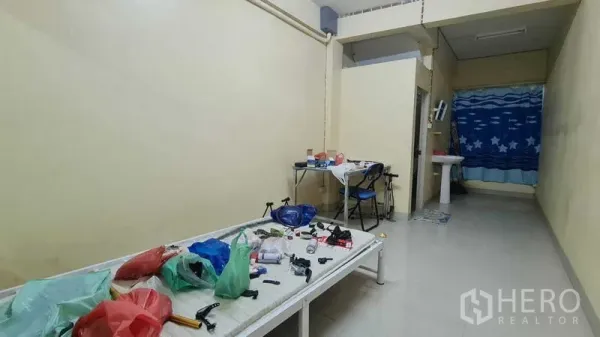 Shophouse for sale in Watthana, Bangkok - Narrow interior room with workbench, small sink, and cream walls.