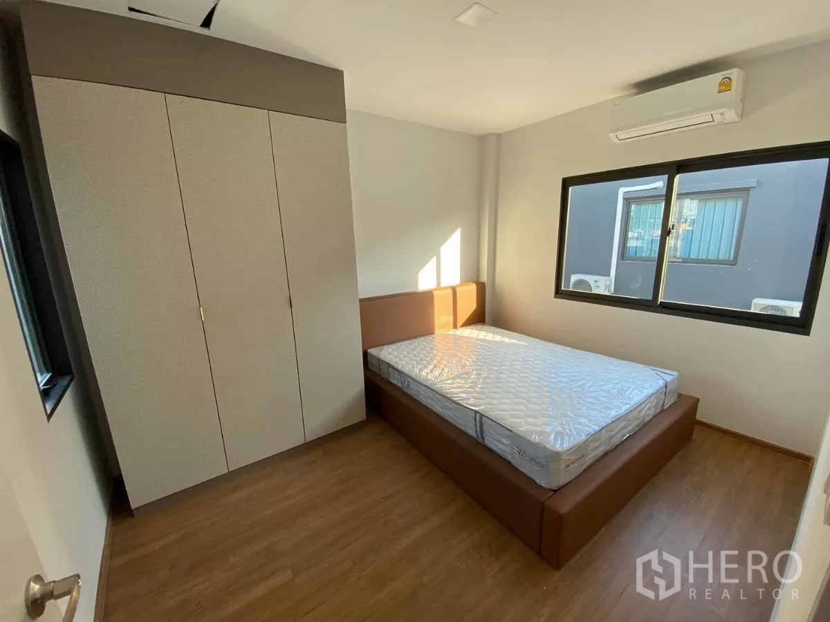 Townhouse for rent in Bang Phli, Samut Prakan - Third bedroom with bed, wardrobe, air conditioner and dual windows.