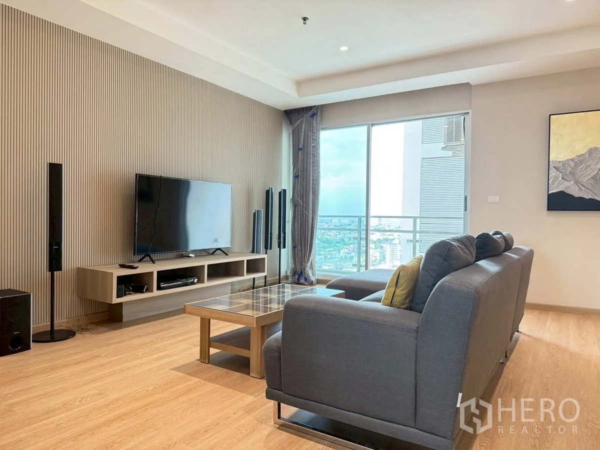 Condominium for rent or sale in Khlong Toei, Bangkok - Living room with sofa set, TV console and balcony city skyline view.