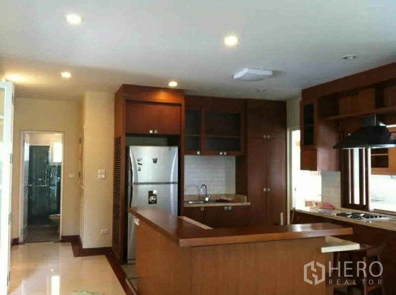 独立式住宅 出租在Phra Khanong, Bangkok - 木质橱柜的现代厨房，岛台、不锈钢冰箱与嵌入式炉灶