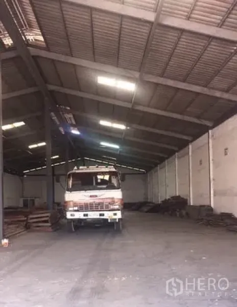 Warehouse for rent in Chachoengsao - Spacious warehouse interior with high clear-span steel roof, concrete floor, skylights and a parked truck.