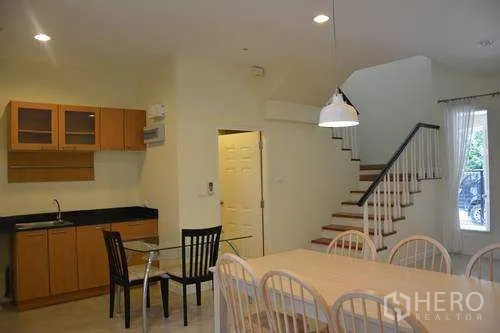 Home Office for rent in Wang Thonglang, Bangkok - Dining area beside pantry kitchen and stairs, glass table and pendant lighting in a Bangkok home office.