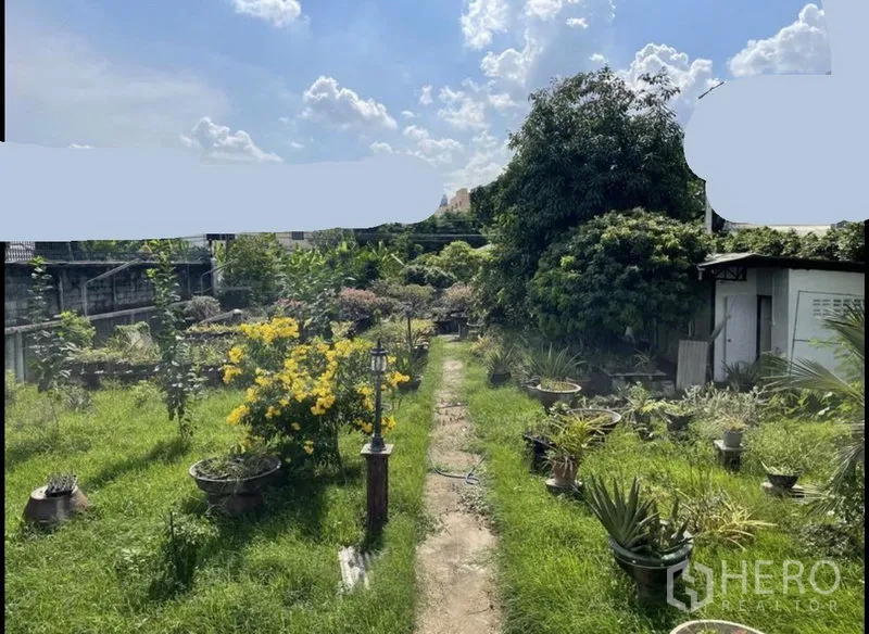 ที่ดิน ขายในSuan Luang, Bangkok - สวนสนามหญ้ากว้าง มีดอกไม้สีเหลือง ทางเดิน และโรงเรือนเล็ก