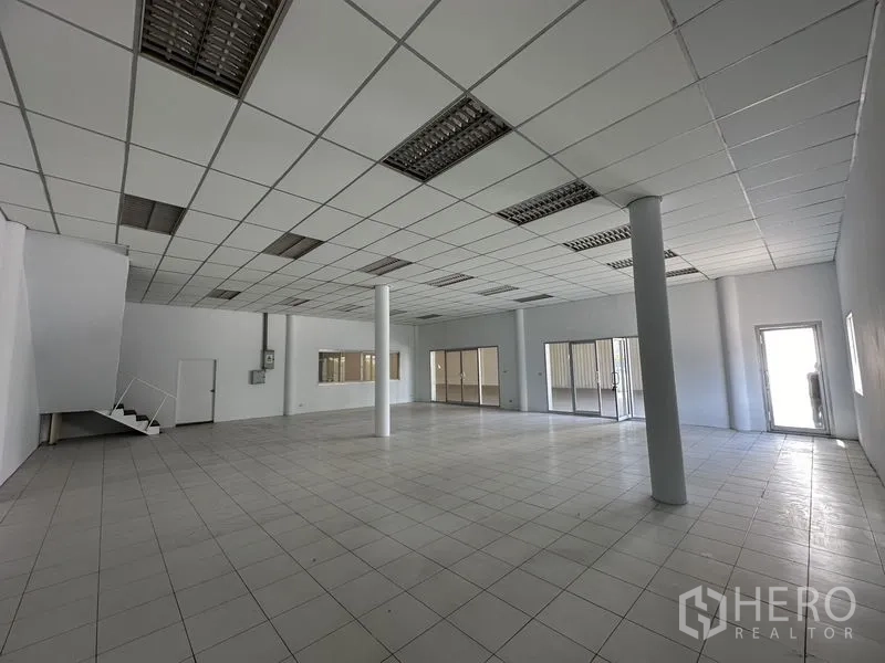 工厂 出租在Khlong Luang, Pathum Thani - 开放式办公区，带立柱、楼梯及多处玻璃入口。