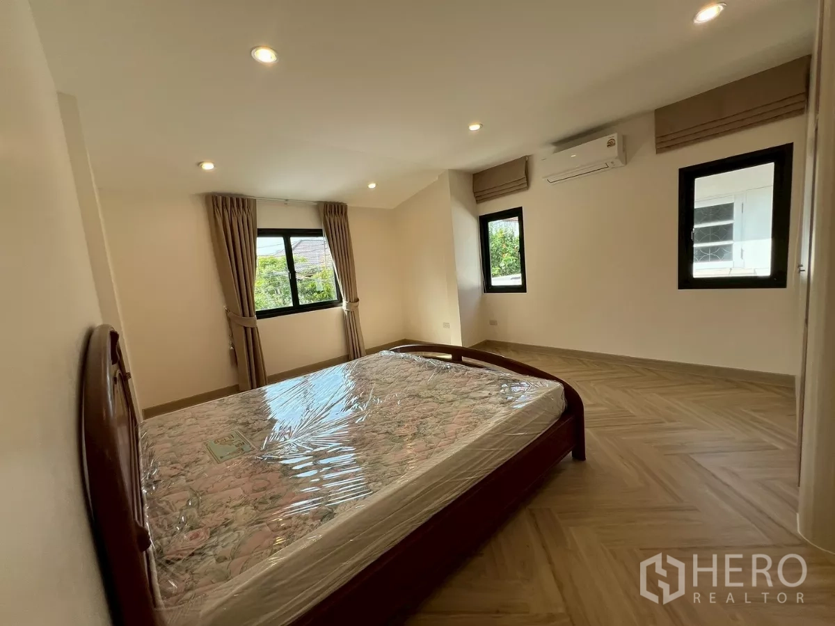 บ้าน ให้เช่าในSuan Luang, Bangkok - ห้องนอนที่สองพร้อมเตียง หน้าต่างหลายด้าน และพื้นไม้โทนอุ่น.