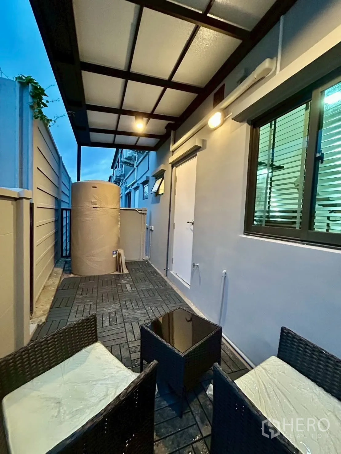 Townhouse for rent in Bang Phli, Samut Prakan - Covered side patio with outdoor seating and water tank along tiled walkway.