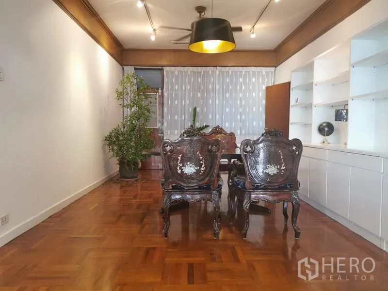 房间 出租在Khlong Toei, Bangkok - 正式餐厅，雕花餐椅、黑色吊灯与盆栽。