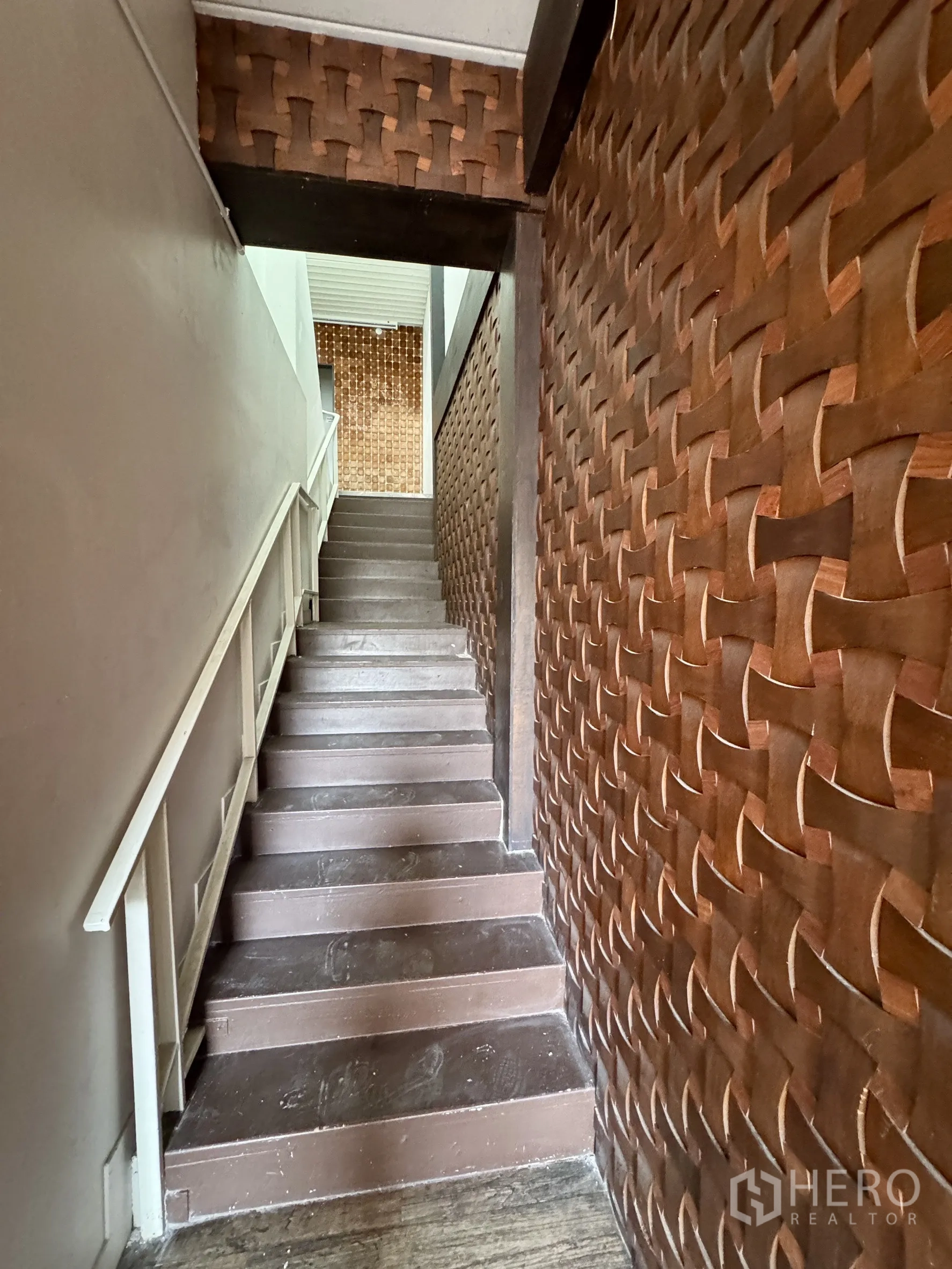 Shophouse for rent in Sathon, Bangkok - Wood-accent staircase with woven-pattern wall panels.