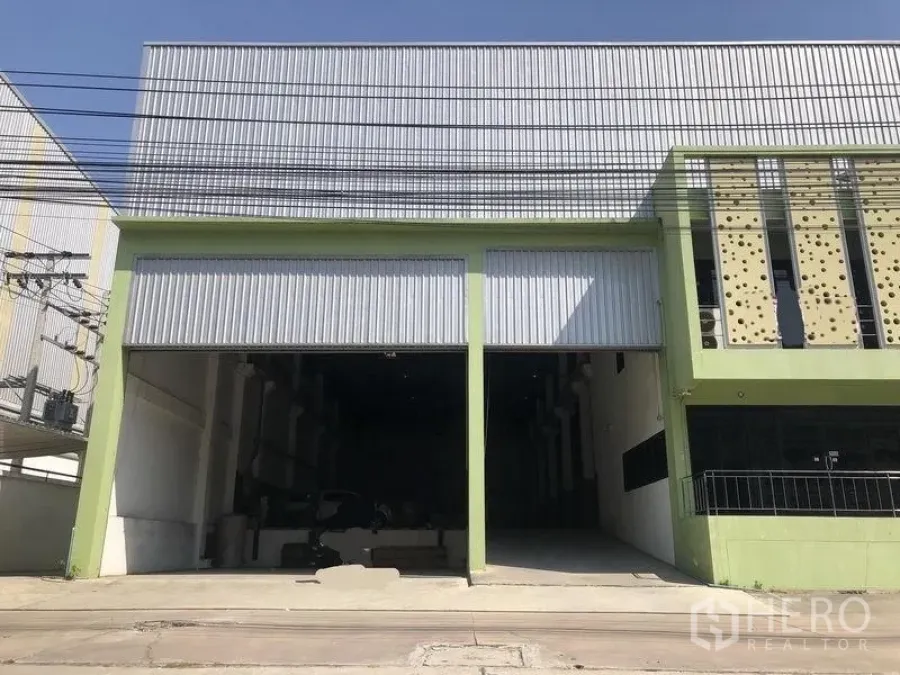 โรงงาน ขายในBang Phli, Samut Prakan - ด้านหน้าโรงงานติดถนน โครงสร้างสีเขียว ประตูม้วนคู่ เพดานสูง และทางรถเข้าออกกว้างในย่านบางพลี