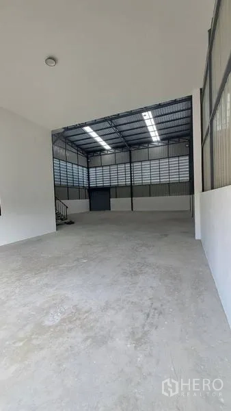 Warehouse for rent in Lam Luk Ka, Pathum Thani - Covered loading area leading to a high-clearance warehouse bay with steel roof and concrete floor.