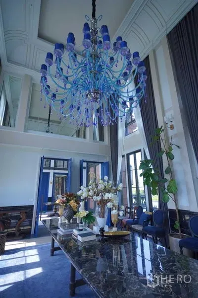 Detached House for sale in Bang Kapi, Bangkok - Double-height lounge featuring a grand blue chandelier and marble table.