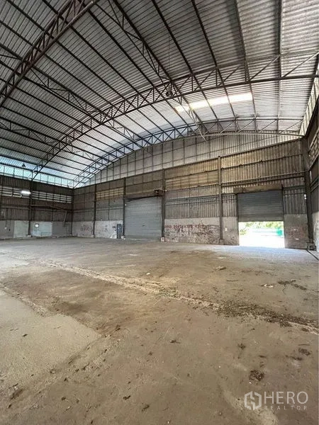 Warehouse for rent in Sam Phran, Nakhon Pathom - High-clearance warehouse hall with several roller doors allowing drive-in access.
