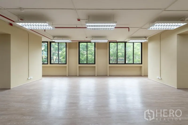 办公空间 出租在Chatuchak, Bangkok - 明亮工作区，整排高窗与中性色墙面，可见树景，适合出租办公。
