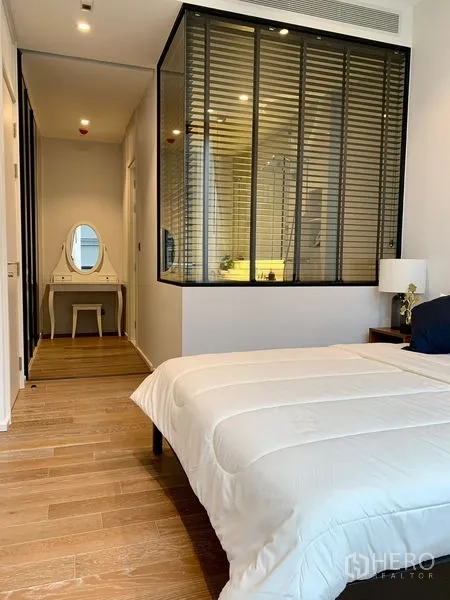 Condominium for rent in Pathum Wan, Bangkok - Bedroom looking toward corridor and vanity, wood flooring and glass bathroom partition.
