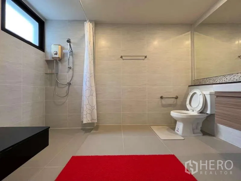 Detached House for sale in Prawet, Bangkok - Large tiled bathroom featuring a walk-in shower with water heater, toilet, and wide mirror.