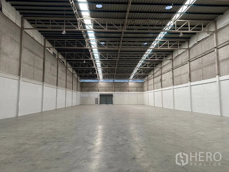 Factory for rent in Si Racha, Chon Buri - Vast empty warehouse interior with high ceiling, skylights and smooth concrete floor.