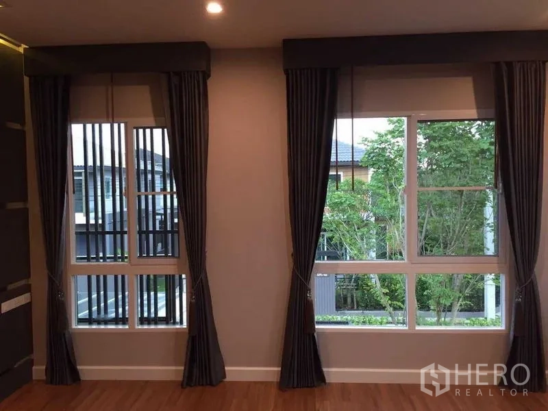 Townhouse for sale in Bang Khae, Bangkok - Upper-floor room with large windows, dark drapes and leafy neighborhood views.