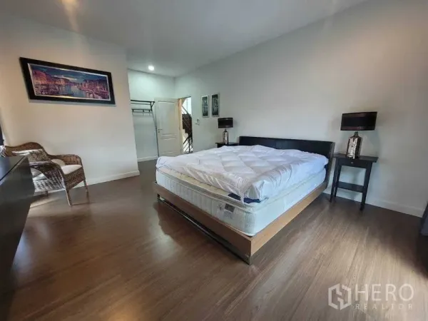 独立式住宅 出租或出售在Prawet, Bangkok - 宽敞主卧，木地板、床与床头柜。