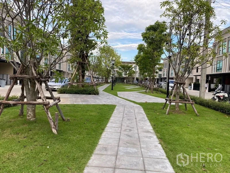 Townhouse for rent in Bang Kapi, Bangkok - Landscaped communal garden with walking paths, trees, and townhomes on both sides.