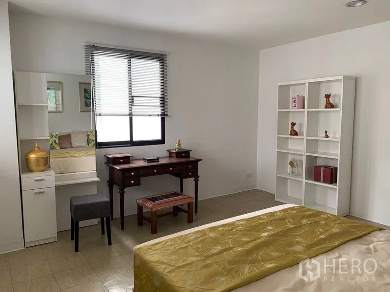 Townhouse for rent in Watthana, Bangkok - Spacious bedroom with desk, shelving and window allowing natural light.