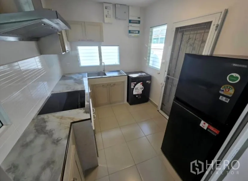 Detached House for rent in Bang Phli, Samut Prakan - Compact kitchen with sink, refrigerator, washing machine and back door.