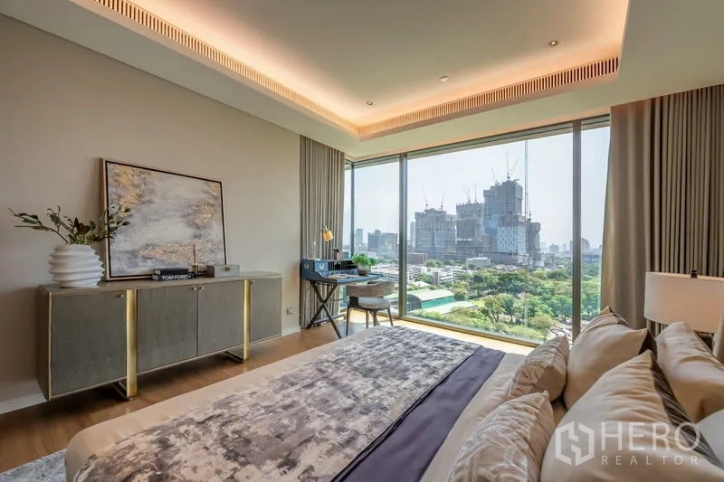 Condominium for rent or sale in Pathum Wan, Bangkok - Bedroom cityscape view with desk by window and greenery below.