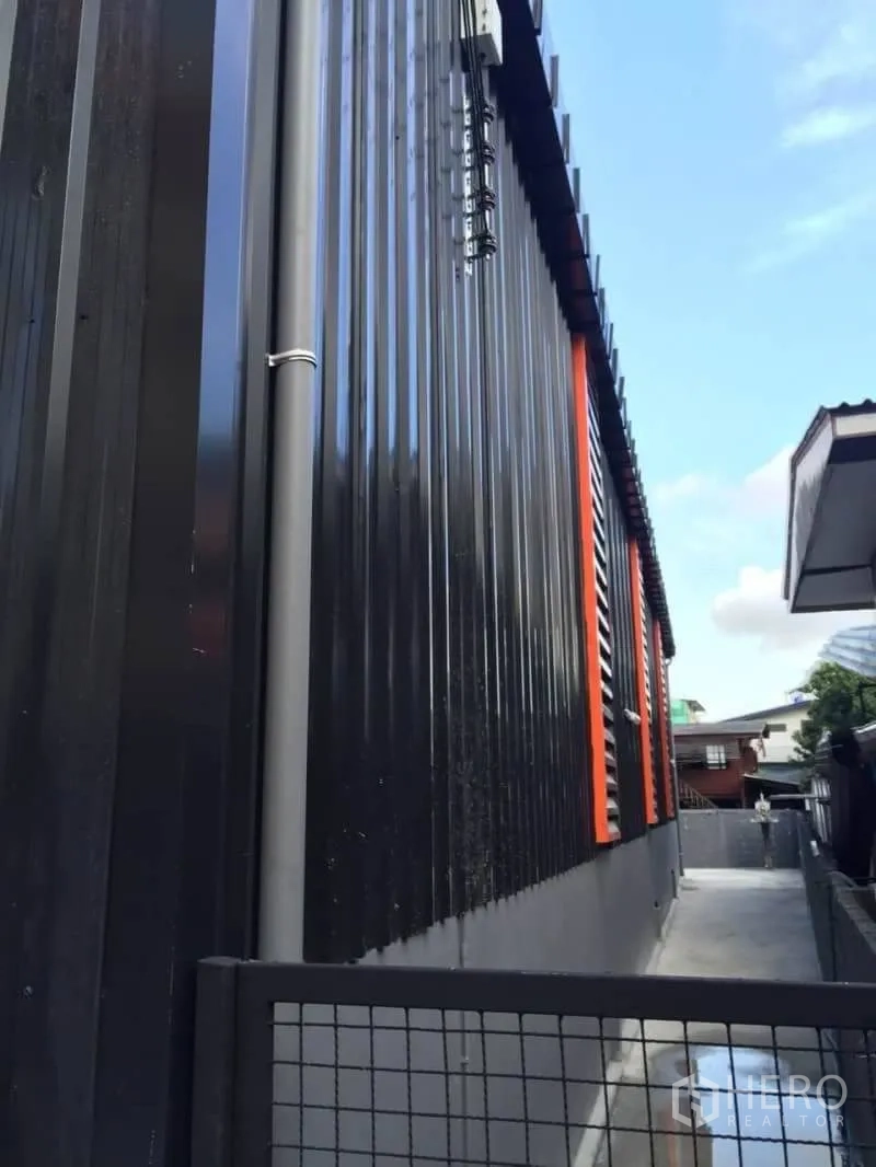 Warehouse for rent in Lat Phrao, Bangkok - Side exterior corridor with metal cladding and a security gate.
