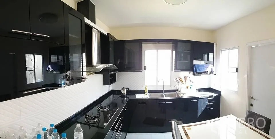Detached House for rent in Pathum Thani - Modern black gloss kitchen with gas hob, range hood, white backsplash and double sink