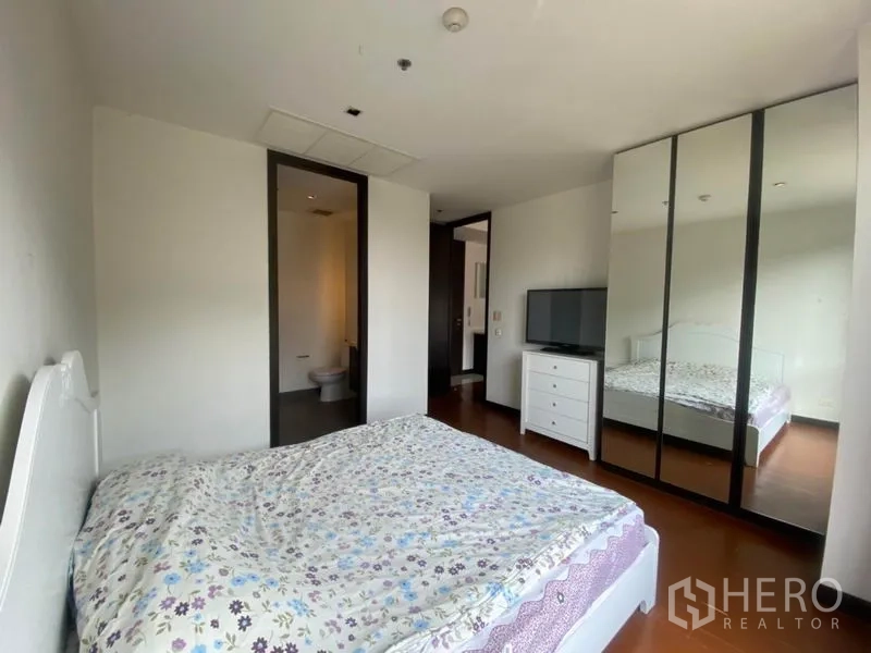 Condominium for rent in Yan Nawa, Bangkok - Primary bedroom with mirrored wardrobe, TV console and entry to ensuite.
