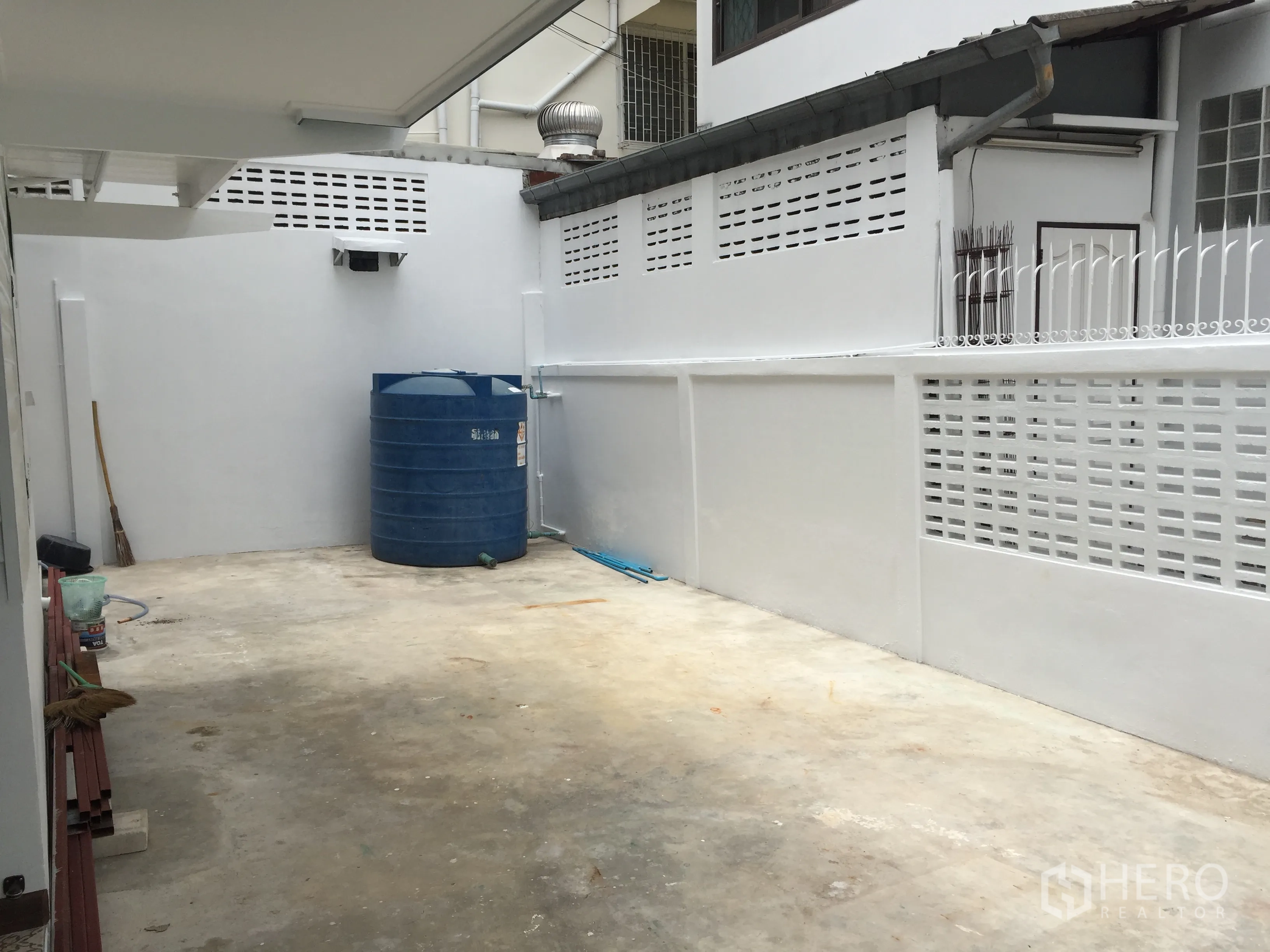 Detached House for rent in Bang Rak, Bangkok - Walled side yard with concrete floor and a large blue water storage tank.