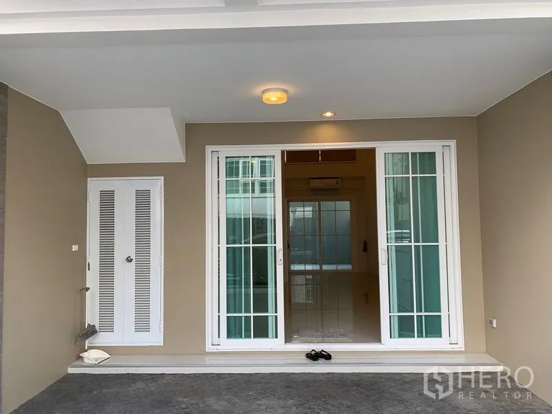 ทาวน์เฮาส์ ให้เช่าในBang Na, Bangkok - เฉลียงหน้าบ้านมีหลังคาพร้อมที่จอดรถ ประตูกระจกบานเลื่อนสีขาวและตู้เก็บของ