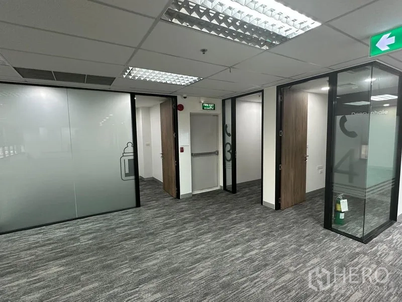 Office Space for rent in Khlong Toei, Bangkok - Hallway with glass meeting rooms and emergency exit doors in a modern office.
