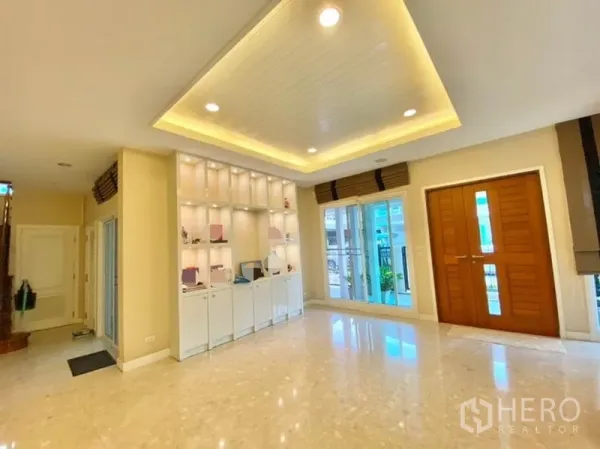 独立式住宅 出售在Khan Na Yao, Bangkok - 采光充足的客厅，大理石地面、嵌灯吊顶、内置展示柜与木质双开门。