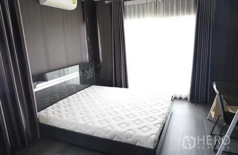 Detached House for rent in Suan Luang, Bangkok - Master bedroom with large window, dark curtains, air-conditioning and bed frame.