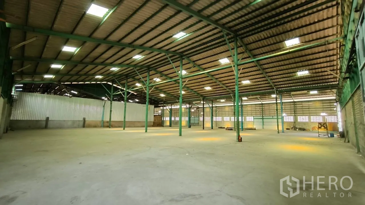Factory for rent in Mueang Samut Prakan, Samut Prakan - Spacious warehouse hall with green steel columns and overhead lighting.